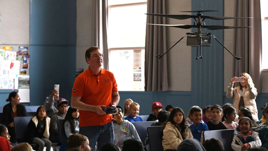 Man operating mini helicopter in front of children